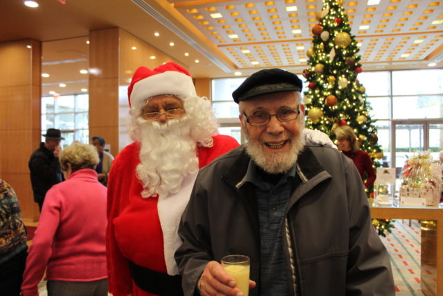Man smiles while standing beside Santa